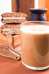 Mug of cocoa on a table nearby with old book and chocolate biscu