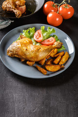 Roasted chicken legs with potato wedges and tomatoes