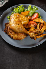 Roasted chicken legs with potato wedges and tomatoes