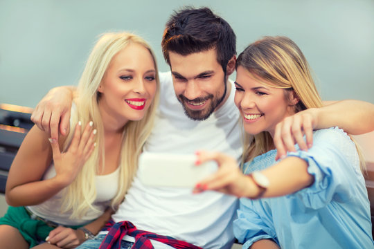 Three friends taking a selfie outdoors on sunny summer day