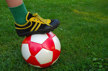 Plakat baby foot on a soccer ball on green grass
