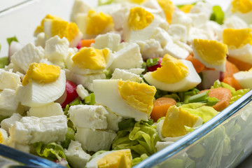 Salad with eggs, feta cheese and carrot in glass bowl