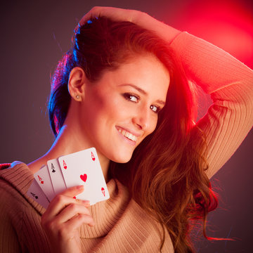 Beautiful brunette holding four aces as a sign for poker game, g