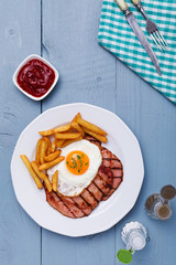 English breakfast with grilled ham, fried egg and french fries.