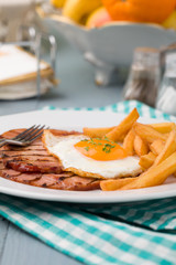 English breakfast with grilled ham, fried egg and french fries.