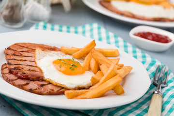 English breakfast with grilled ham, fried egg and french fries.