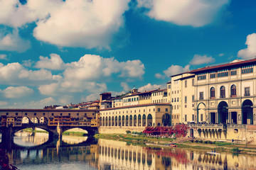 View from the river to the famous italian medieval bridge - Ponte Vecchio in Florence with blue sky and clouds, travel outdoor Italy sightseeing background