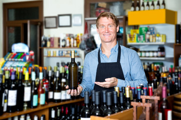 Male seller with wine bottle in hands