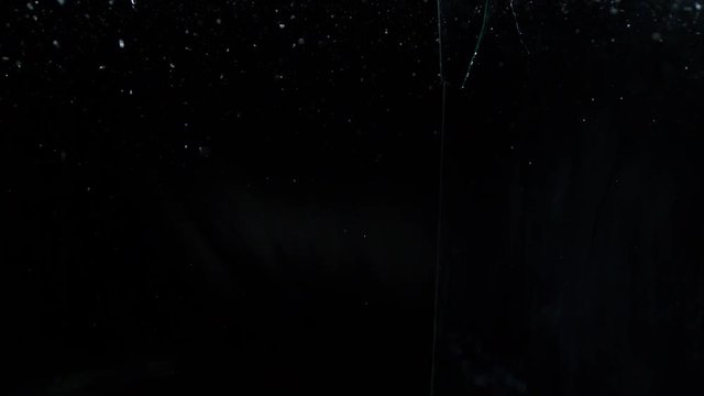 Glass shards on black, breaking over the camera in slow motion