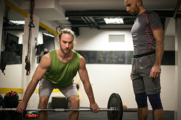 Fototapeta na wymiar Adult man doing weightlifting in a gym.