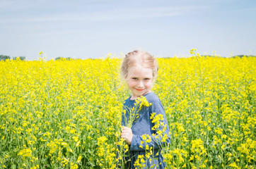 Fototapeta premium happy girl on blooming rapeseed field in summer