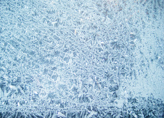 Light bright blue white frost snowflake beautiful pattern on the window. Winter season picture - empty background wallpaper for text