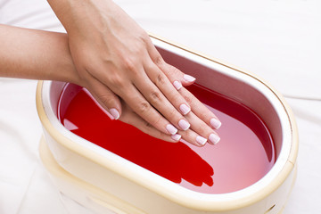 Process paraffin treatment of female hands in beauty salon 