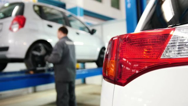 Car details - auto headlight close up in diagnostic service - mechanic working near lifted car
