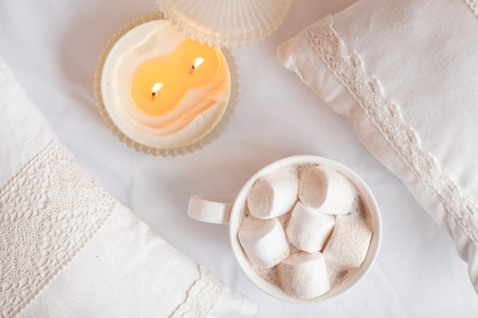 White cup of hot cocoa with marshmallows on white wooden backgro
