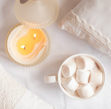 White cup of hot cocoa with marshmallows on white wooden backgro