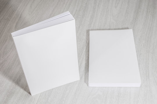 Real 3D paperback white books on a wood background