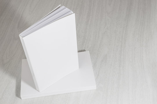 Real 3D paperback white books on a wood background