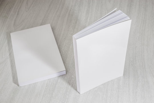 Real 3D paperback white books on a wood background