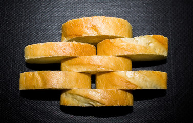 loaf of white bread baguette sliced ​​on a black background