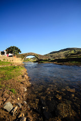Fototapeta na wymiar Old Roman bridge across small brook, village of Cheleiros, Portugal