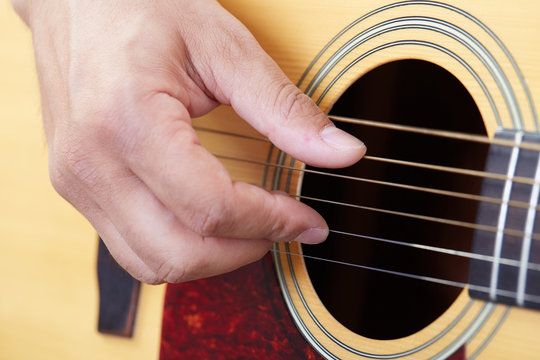 Close up of guitarist hand playing acoustic guitar