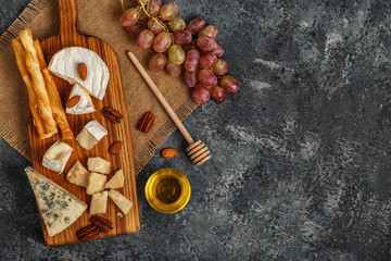 Assortment of cheese with honey, nuts and grape.