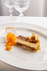 Cheesecake with white chocolate, hazelnuts and pumpkin confit on white plate