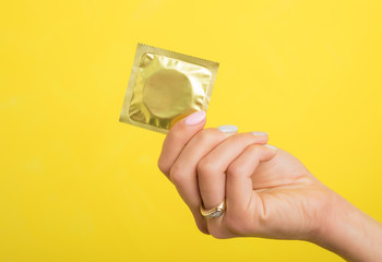 Woman holding a condom - obrazy, fototapety, plakaty