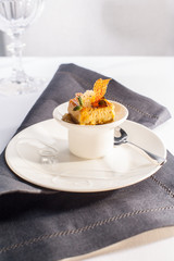 Chicken liver creme caramel with cinnamon salsa in white porcelain, on black tablecloth.