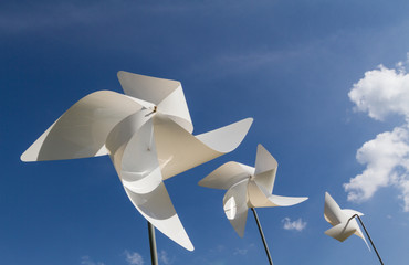 White pinwheel and windmill with blue sky and white cloud background, symbol of happiness