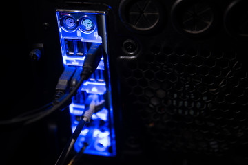Blackout, blurred borders. Close up of blue network cables connected to black switch glowing in the dark