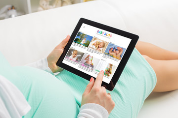 Pregnant woman reading baby blog on tablet