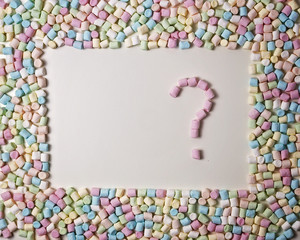 Heart in the frame of colorful mini marshmallows on white background. Top view