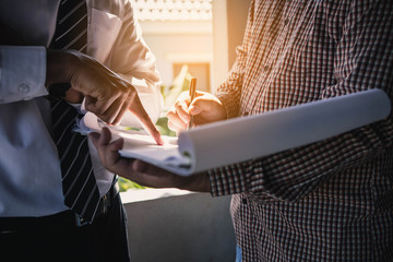 Management consulting with engineers working at construction site and holding blueprint in his hand for management business plan. Consult concept.