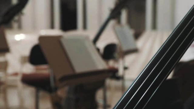 Close up dolly shot of cello fingerboard on scene in an empty classical style concert hall