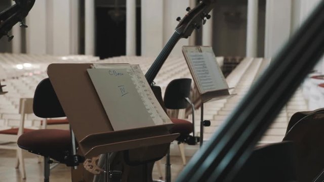 Close up dolly shot of cellos and music stands on scene in an empty classical style concert hall