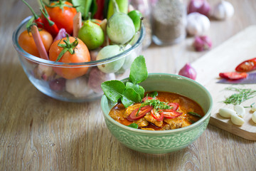 Chicken panang curry in green bowl and ingredient on wooden back