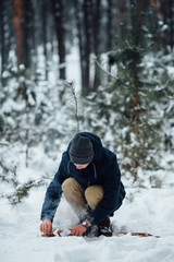 Man kindle bonfire in winter snowy forest