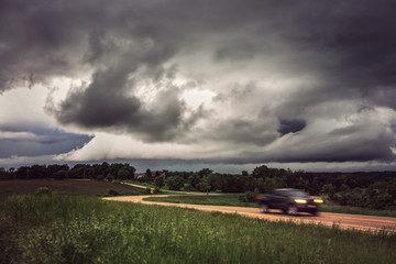 Car on a country road with a stormy sky