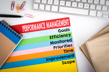 Performance Management. Office desk with a computer keyboard and color pages.