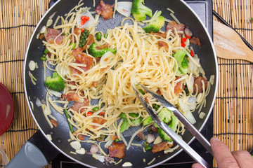 Chef stir fried Spaghetti with tongs