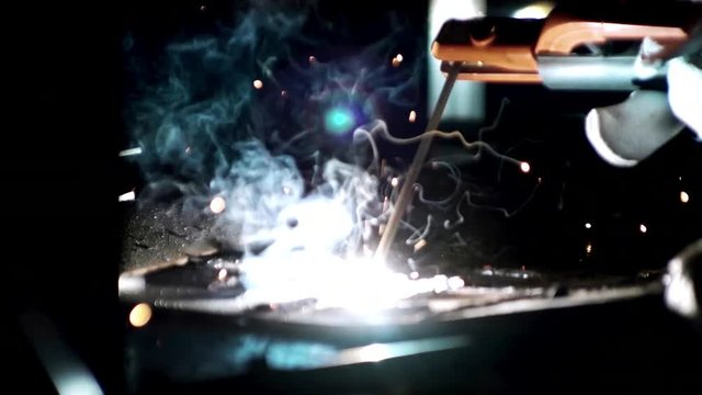 Welder worker welding metal by electrode at the factory
