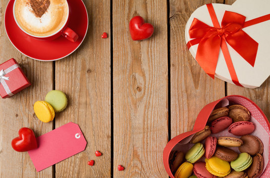 Valentines day concept with macarons, coffee cup and gift box over wooden background. Top view from above