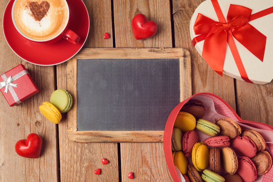 Valentines day concept with macarons, coffee cup and chalkboard over wooden background. Top view from above