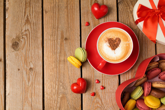 Valentines day concept with macarons and coffee cup over wooden background. Top view from above