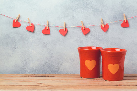Valentines day concept with coffee cups and heart shapes over rustic background with garland