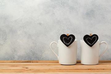Valentines day concept with coffee cups and chalkboard heart shapes on wooden table