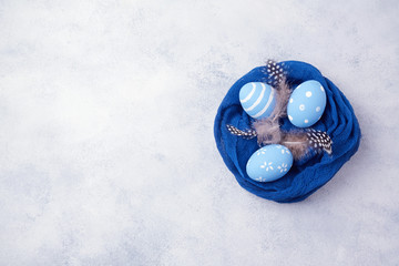 Easter holiday concept with egg decoration in cloth over white board background. View from above