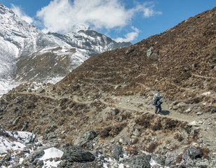 Porter walk on a trail in the valley Chhukung against peak Ama Dablam (6814 m) from the valley of...